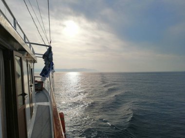 Mavi deniz manzarası bulutlu bir gökyüzünün altında bir tekneden görünüyor.