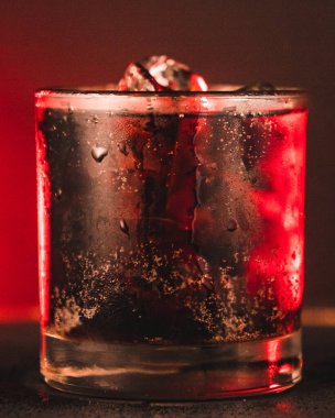 Kırmızı neon arka planda buzlu bir gazoz içeceğinin dikey yakın çekimi.
