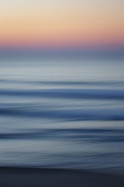 Gün batımında sahildeki güzel mavi deniz dalgalarının yakın çekimi.