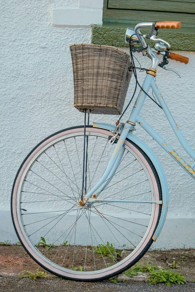 一辆蓝色城市自行车的垂直特写镜头 它在方向盘附近的一个篮子里 在墙的后面 — 图库照片