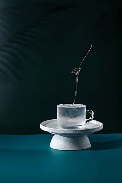 Чашка Холодной Жидкостью Левитационной Каплей Синем Столе Возле Черной Стены — стоковое фото
