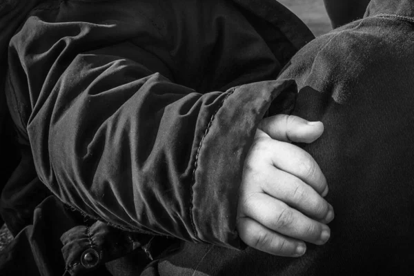 A grayscale shot of a child hand hugging another child - protection, brotherhood concept