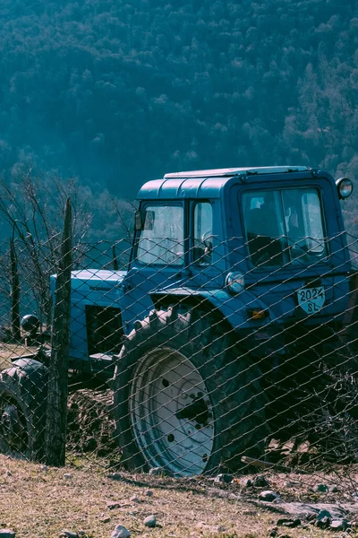 Ein Vertikaler Schuss Eines Traktors Der Gegen Bewaldete Berge Parkt — Stockfoto