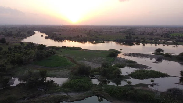 背後に夕日を背景に平野に流れる川 — ストック写真