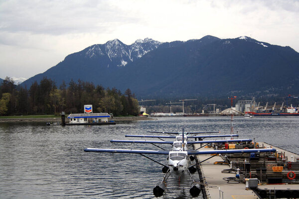 Ряд гидросамолетов у причала против горного хребта. Ванкувер, Британская Колумбия, Канада.