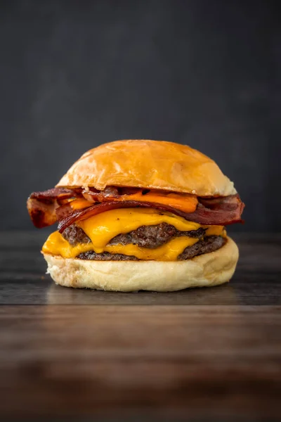 Pionowe Ujęcie Pysznego Soczystego Burgera Drewnianym Stole — Zdjęcie stockowe