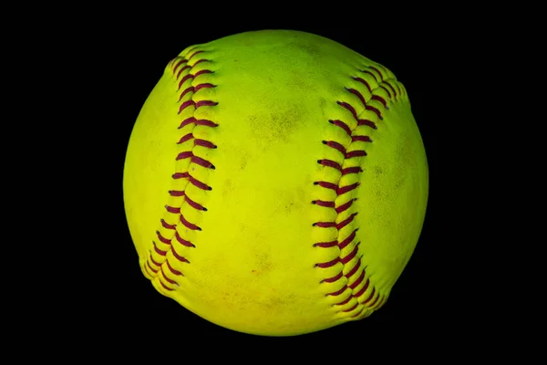 A closeup photo of a used softball isolated on a black background