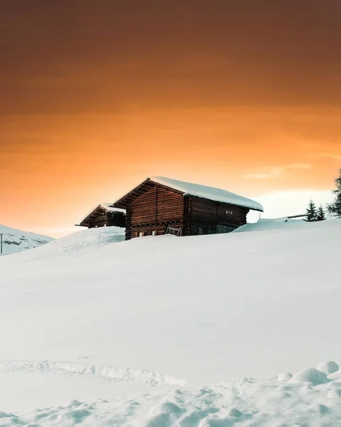Vertikální Záběr Starého Dřevěného Domu Pokrytého Sněhem Při Západu Slunce — Stock fotografie