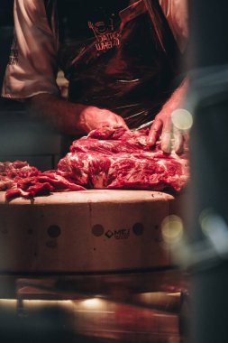 Lokantada bıçakla et kesen bir kasap dikey pozu.
