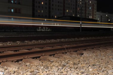 Gece vakti, tren raylarının uzun pozlu ışıklarıyla yakın plan çekimi.