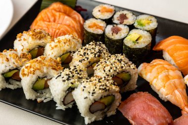 Beyaz arka planda siyah bir tabakta sushi 'nin üst görüntüsü