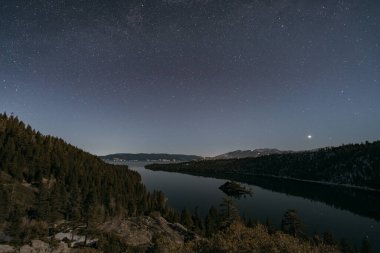 Yıldızlı bir gökyüzünün altında süslü püslü bir nehir manzarası..