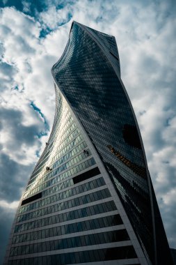 Moskova, Rusya 'da bulutlu bir gökyüzünün yansımasıyla modern bir spiral binanın alçak açılı görüntüsü.