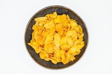 Beyaz bir yüzeyde izole edilmiş bir kasede gevrek mısır gevreğinin üst görüntüsü.