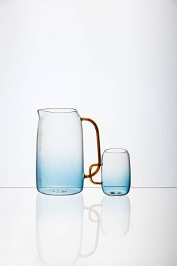 Cam mavi şeffaf fincanın dikey görüntüsü ve beyaz arka planlı meyve suyu kabı.