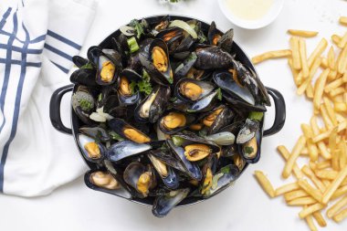 Beyaz mermer bir masada patates kızartması ve sos ile Belçika midyelerinin üst görüntüsü.