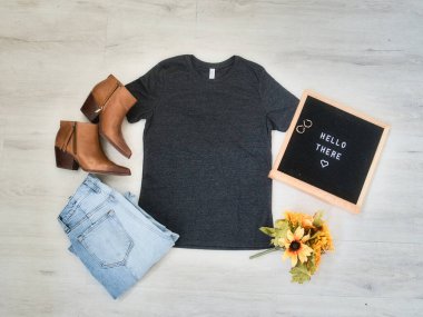 Siyah bir tişört, kot pantolon ve bir çift kahverengi deri çizme.