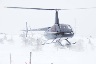 Finlandiya, Laponya 'da karlı bir dağda iniş yapan siyah bir helikopter