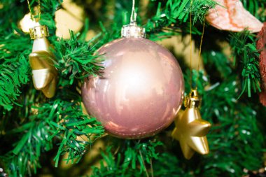 Küçük altın yıldızlı büyük pembe bir Noel ağacı süsü.
