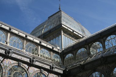 İspanya, Madrid 'de bir ışık gününde ufukta mavi gökyüzü olan Kristal Saray' ın alçak açılı bir görüntüsü.