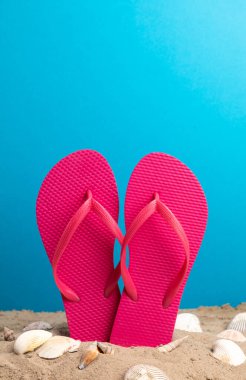 Mavi arka planda pembe parmak arası terliklerin yakın çekimi.