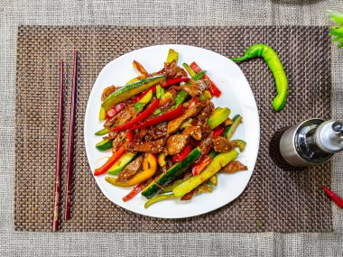 Biftek dilimleri ve farklı sebzelerle dolu bir tabağın üst görüntüsü.