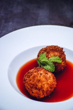 Beyaz tabakta iki İtalyan Arancini pirinç topunun dikey yakın çekimi.