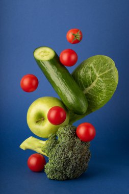 Mavi arka planda uçan sebzelerin dikey çekimi