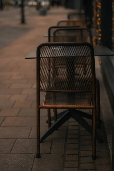 夜の椅子付きの屋外カフェの空のテーブルの垂直ショット — ストック写真