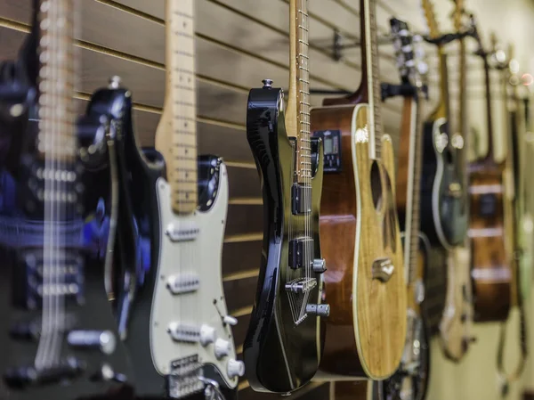 音楽店の壁に掛けられた様々な種類のギターのクローズアップ — ストック写真