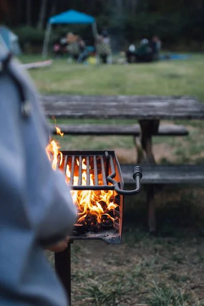 篝火在野餐桌旁的室外烤炉中燃烧着的火焰的垂直镜头 — 图库照片