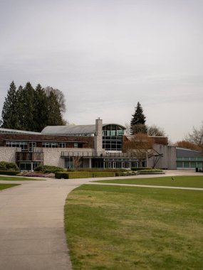 Modern bir binanın dikey görüntüsü ve Burnaby, Kanada 'da ağaçlı ve çiçekli bir bahçe.