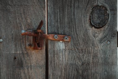 Paslı kapı mandalı olan ahşap çit tahtalarının yakın çekimi.