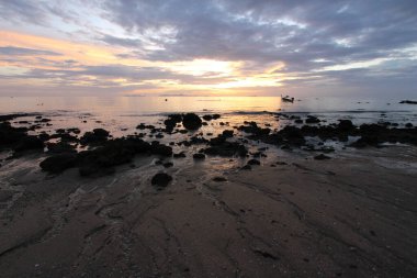 Güneşin batışıyla boyanmış güzel deniz, bulutlu bir gökyüzünün altında