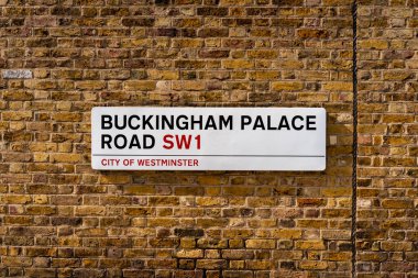 An iconic London road sign for 'Buckingham Palace Road' on a red brick, wall of Buckingham Palace
