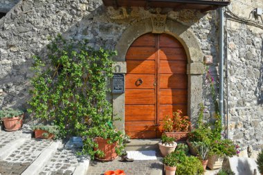 Patrica 'da, Frosinone, İtalya' da bir köyde esrar bitkileri olan eski bir evin kahverengi kapısının güzel bir dış görüntüsü.