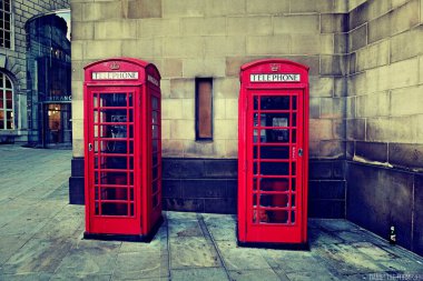 Manchester, İngiltere 'de inşaat duvarının yanında geleneksel kırmızı telefon kulübeleri.