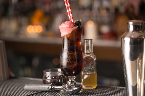 テーブルの上にグラスボトルとスプーンの近くにストロー付きブラックチェリーカクテルのクローズアップ — ストック写真