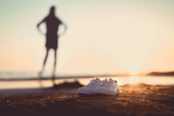 一双白色的鞋子 背景模糊 海滩上一个女孩的轮廓 — 图库照片