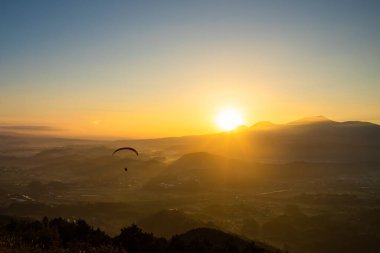 Gün doğumunda Paraglider 'la dağların üzerinde uçan insan görüntüsü
