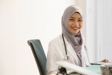 Kabinesinde oturan Güneydoğu Asyalı bir kadın doktor.