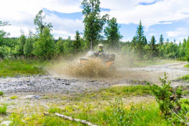 Arazide toz ve çamurla çevrili bir motorsikletçi.