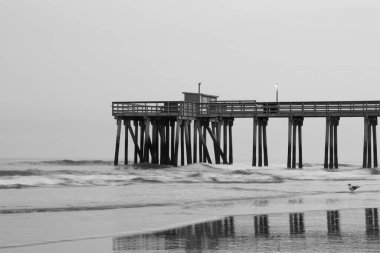 Dalgalı denizin ve kasvetli bir günde ahşap iskelenin ahenkli manzarası