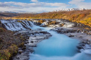 Bruarfoss Şelalesi 'nin görkemli suları ve İzlanda' nın Brekkuskogur şehrinde mavi bulutlu bir gökyüzü ile muhteşem bir manzara.