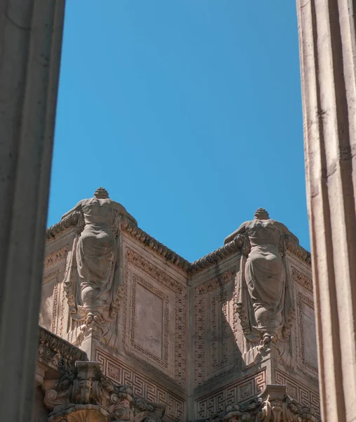 澄んだ青空の下で古代の建物の中に構築された2つの彫刻の低角度ショット — ストック写真