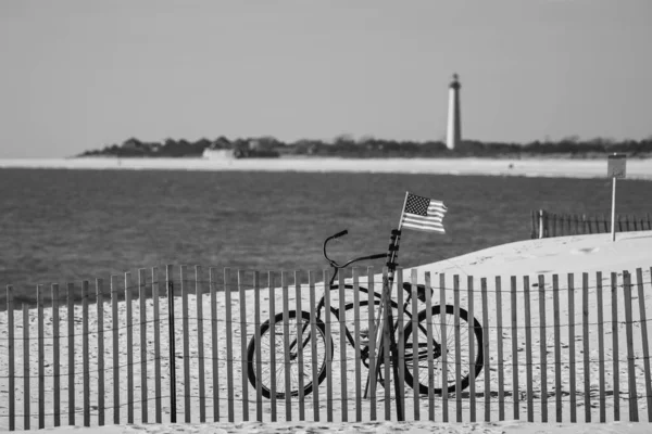 A grayscale shot of a parked bicycle with USA flag at the Cape May shore during Christmas