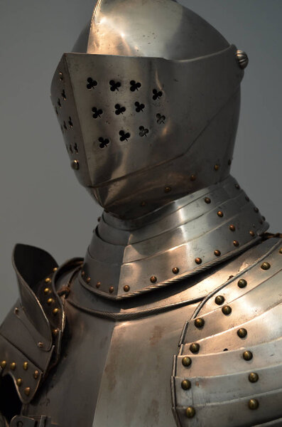 A vertical shot of the top of medieval knight armor made of metal with clover-shaped holes in a museum