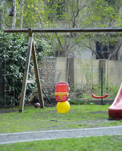 Ein Vertikaler Schuss Roter Kunststoff Schaukelt Tagsüber Auf Einem Rasenspielfeld — Stockfoto