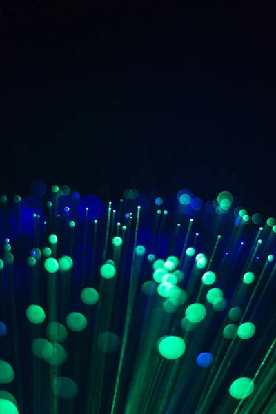 An abstract background of a Bundle of optical fibers with green light on a Black background.