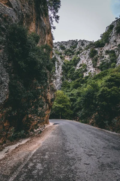 Tiro Vertical Uma Estrada Asfalto Vazia Entre Montanhas Rochosas Cobertas — Fotografia de Stock
